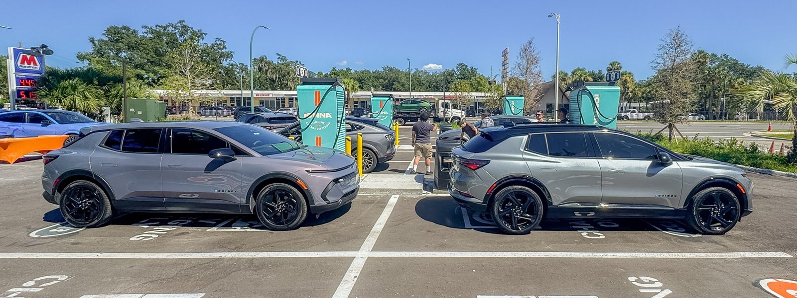 Two Chevrolet Equinox EVs parked across from each other along a row of IONNA dispensers